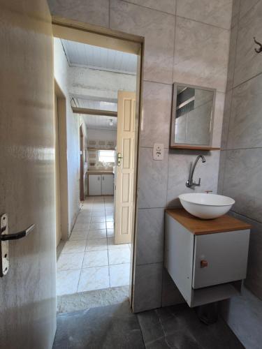 a bathroom with a sink and a mirror and a hallway at Casa Hermena in Santa Vitória do Palmar