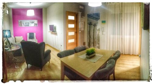 a dining room with a table and chairs and pink walls at Apartamentos Alcazar de Baeza in Baeza