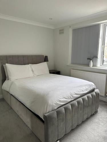 a bedroom with a large bed with white sheets and a window at Luxury 2-Bed Apartment with Parking & Garden in Borehamwood