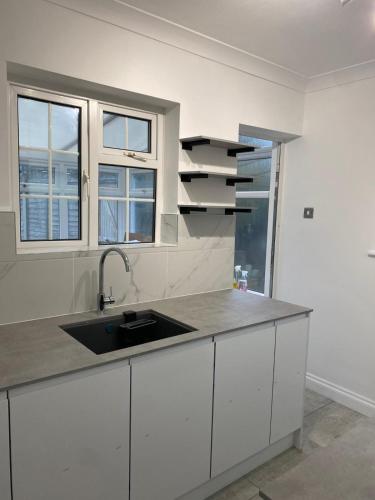 a kitchen with a sink and two windows at Luxury 2-Bed Apartment with Parking & Garden in Borehamwood