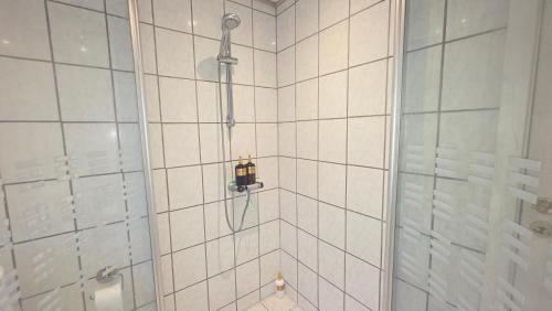 a shower in a white tiled bathroom at Plads til børnefamilien i hjertet af Esbjerg in Esbjerg