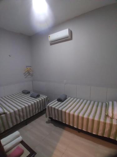 a room with two beds and a white wall at Yanne chalé 1 in Barra Grande