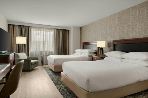 a hotel room with two beds and a television at Sheraton Hotel Metairie New Orleans in Metairie