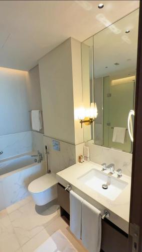 a bathroom with a sink and a toilet and a mirror at ADDRESS RESIDENCES BEACH RESORT BAHRAiN in Rayyā