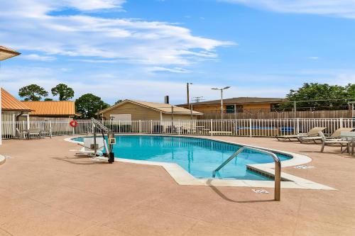 a large swimming pool with a fence at SureStay Studio by Best Western Pensacola in Pensacola