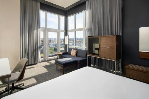 a living room with a tv and a couch and a chair at Courtyard by Marriott Sand City Monterey in Sand City