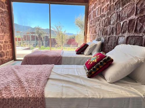 two beds in a room with a brick wall at Villa Al Firdaous in Tiznit