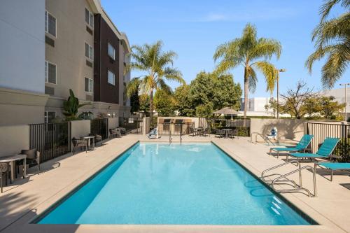a swimming pool with chairs and a building at TownePlace Suites by Marriott Anaheim Maingate Near Angel Stadium in Anaheim