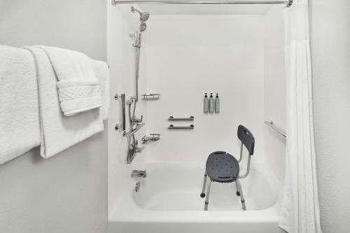 a white bath tub with a chair sitting in it at Courtyard by Marriott Huntsville University Drive in Huntsville