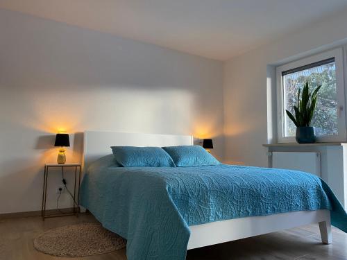 a bedroom with a bed with a blue comforter and a window at Stilvolles Studio im Allgäu in Rettenbach am Auerberg