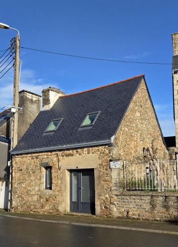 a stone house with a black roof on a street at Maison Ty Bian Prieuré in Pleubian