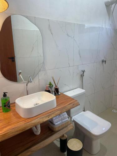 a bathroom with a sink and a toilet and a mirror at Casa Refúgio do Rio in Caraíva
