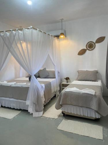 a bedroom with two beds and a canopy at Casa Refúgio do Rio in Caraíva
