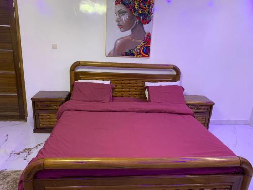 a bedroom with a bed with pink sheets and a painting at Résidence Salt Lake in Pikine