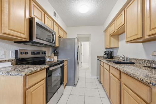 a kitchen with wooden cabinets and a stainless steel refrigerator at Fair Seas Clipper Condo for 6 in Saint Augustine Beach