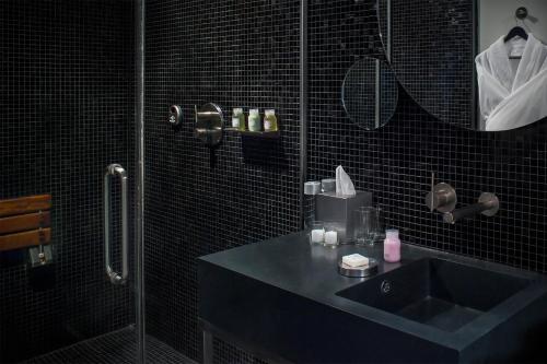 a black bathroom with a sink and a shower at Hotel on Rivington in New York