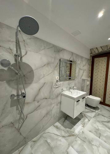 a marble bathroom with a shower and a sink at The White Troy in Sarandë