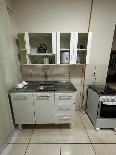 a kitchen with white cabinets and a sink at Apt Aconchegante no Centro de Rolim in Rolim de Moura