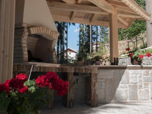 a patio with a stone fireplace with red flowers at Green Life Family Apartments Pamporovo in Pamporovo