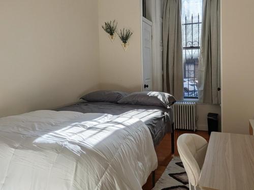 a bedroom with two beds and a table and a window at Times Square Retreat with Private Bathroom and Kitchenette in New York