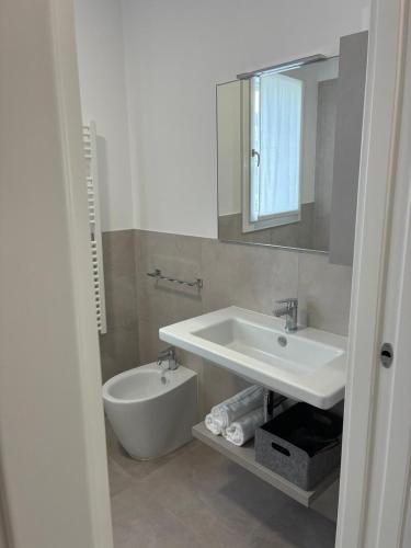 a bathroom with a sink and a toilet and a mirror at Matilde Apartments Caorle in Caorle