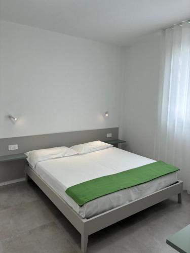 a white bed with a green blanket on it at Matilde Apartments Caorle in Caorle