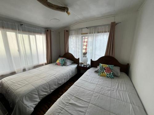 a bedroom with two beds and two windows at Fungi Hostal in Coihaique