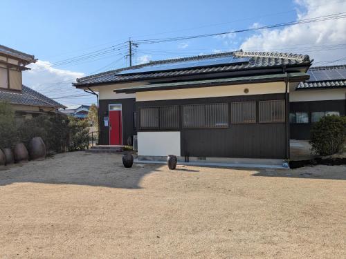 a house with a red door in a dirt yard at Koko House in Kurume