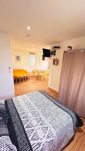 a bedroom with a bed and a room with a table at Bungalow Soleil Sainte-Anne - Plage à pied in Sainte-Anne