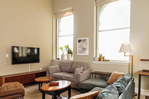 a living room with a couch and a tv at Downtown Luxe 2BR Loft Apt | Sleeps 8 | Walkable in Milwaukee