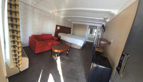a hotel room with a bed and a red couch at Exceed Inn Indianapolis Airport South in Indianapolis