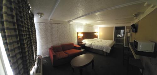 a hotel room with a bed and a couch and a chair at Exceed Inn Indianapolis Airport South in Indianapolis