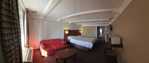 a hotel room with a bed and a red couch at Exceed Inn Indianapolis Airport South in Indianapolis