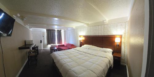 a hotel room with a large bed and a red chair at Exceed Inn Indianapolis Airport South in Indianapolis