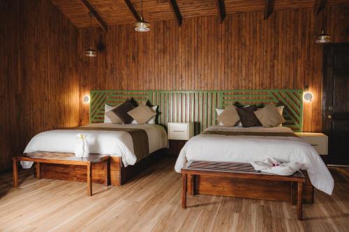 a bedroom with two beds and a table with a bench at Lauraceas Lodge in San Gerardo de Dota