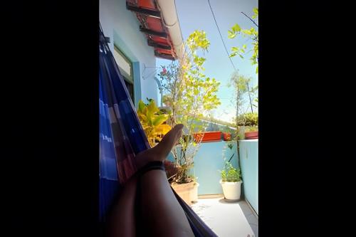 a person sitting in a hammock looking out of a window at Santo Antônio Além do Carmo - apartamento com varanda e vista pro mar, até 3 pessoas in Salvador