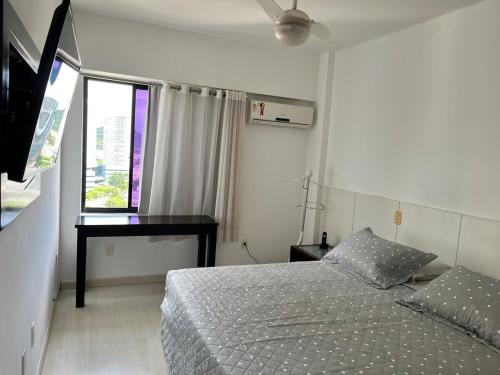 a bedroom with a bed and a desk and a window at Enseada do Suá Golden Gate - Moderno e Espaçoso in Vitória