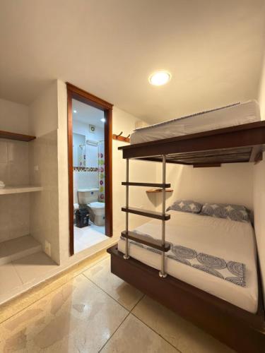 a bedroom with a bunk bed and a bathroom at Hostal El Recreo in Barranquilla