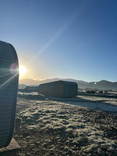 a surfboard sitting on a beach with the sun setting at Killarney Glamping - Ross Road in Killarney