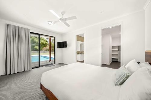 a white bedroom with a bed and a swimming pool at Hinterland Haven with Heated Pool & Lush Surrounds in Mooloolah