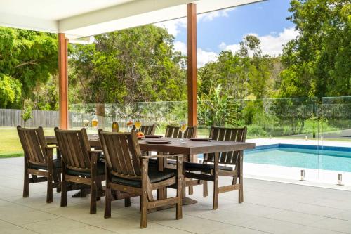 a dining room with a table and chairs and a pool at Hinterland Haven with Heated Pool & Lush Surrounds in Mooloolah