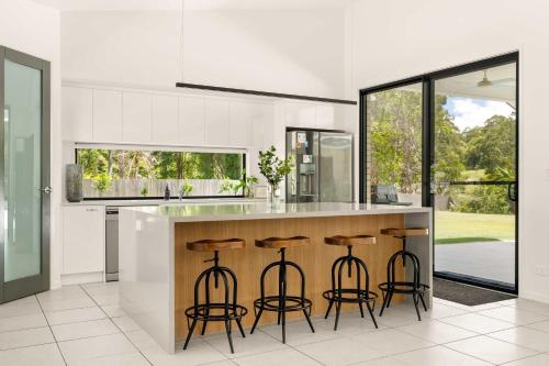 a kitchen with a counter with bar stools at Hinterland Haven with Heated Pool & Lush Surrounds in Mooloolah
