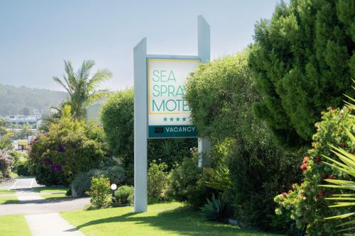 a sign for a sea springs motel in a garden at Sea Spray Motel - Merimbula in Merimbula
