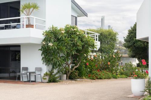 a white building with chairs and flowers in front of it at Sea Spray Motel - Merimbula in Merimbula