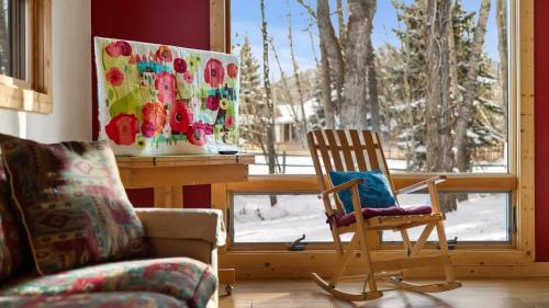 a living room with a rocking chair and a window at Chickadee Chalet in Red Lodge
