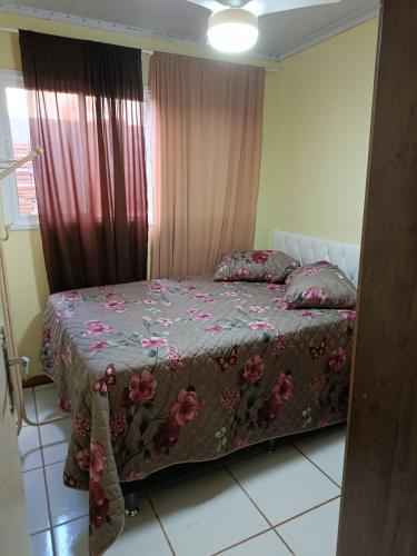 a bedroom with a bed with a floral bedspread at Casa de 1 quarto in Torres