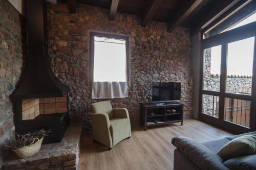 a living room with a stone wall and a couch and a tv at El Paller de Casa Parramon in Peramea