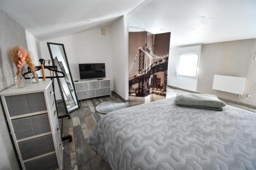 a bedroom with a bed and a dresser and a tv at République Le Nid Douillet in Saint-Dizier