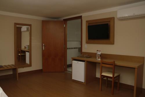 a hotel room with a desk and a television at Hotel Pouso Real in Rio de Janeiro
