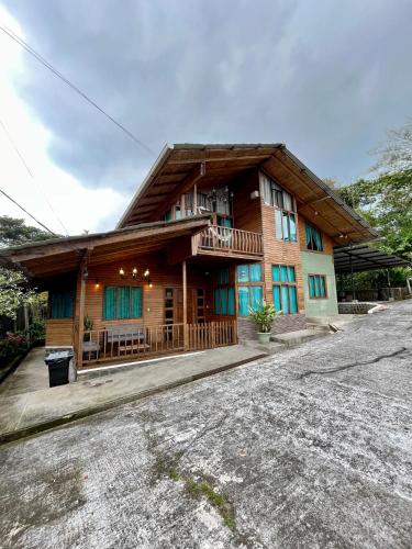 Una gran casa de madera con porche y balcón. en Casa de Emmita, en Puyo